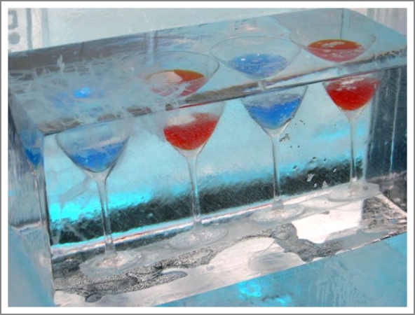 vier Cocktailglser mit blauem und rotem Inhalt im Eisblock